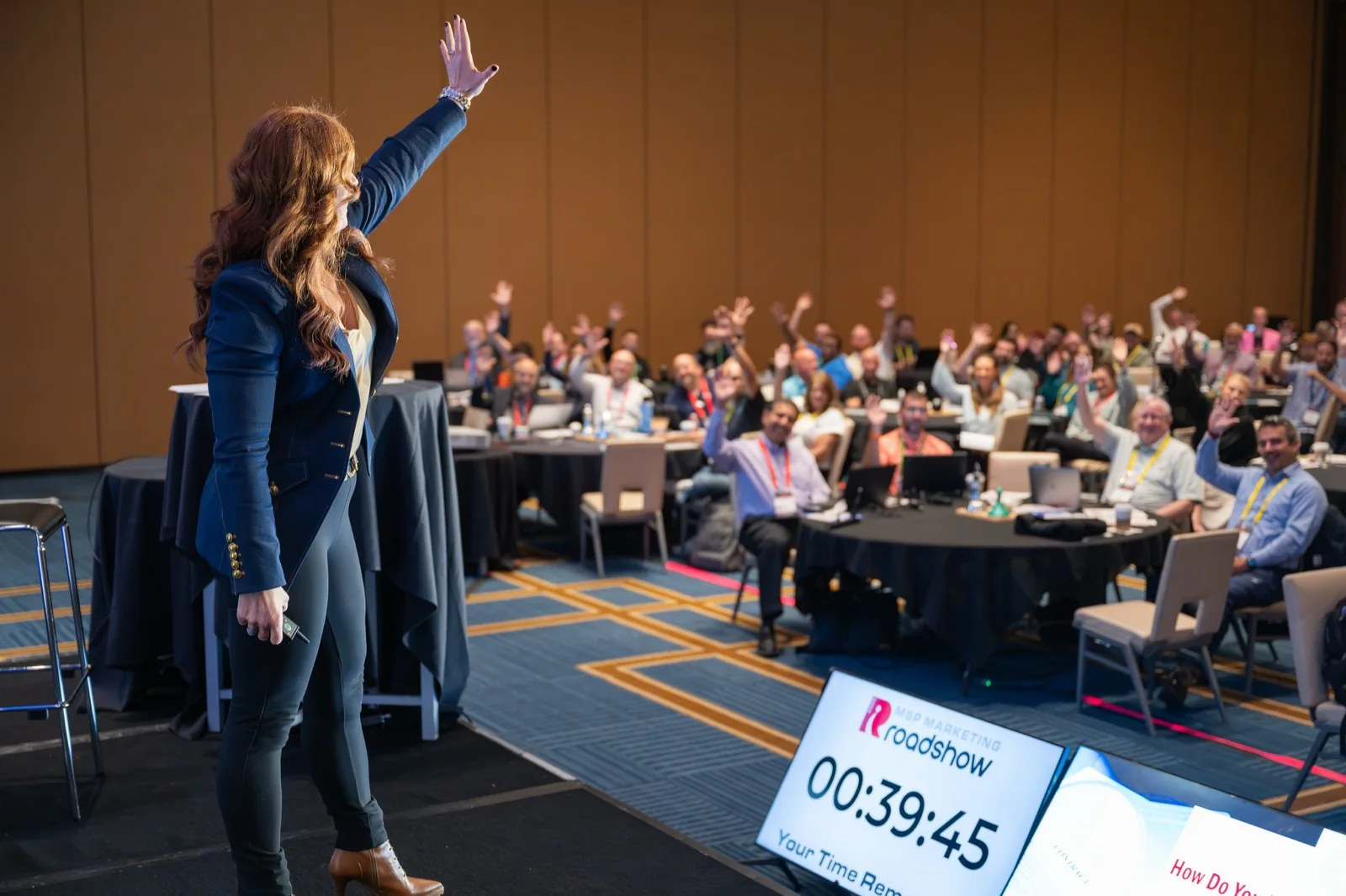 Robin Robins on stage as a room of MSP owners raise their hands